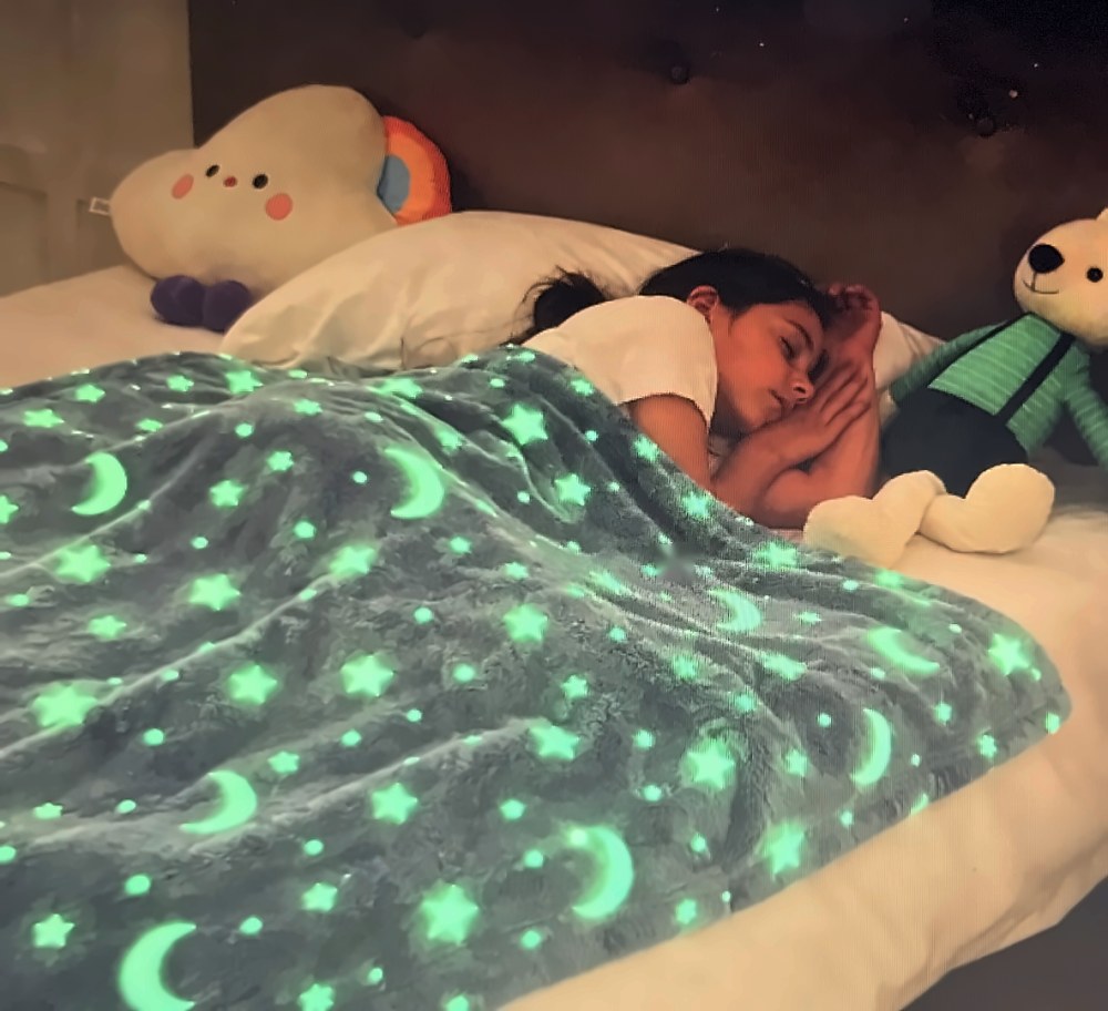 Niña durmiendo bajo la manta Silkbeam que brilla en la oscuridad